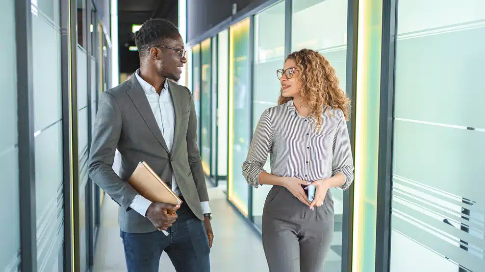 man and woman conversing in an office hallway