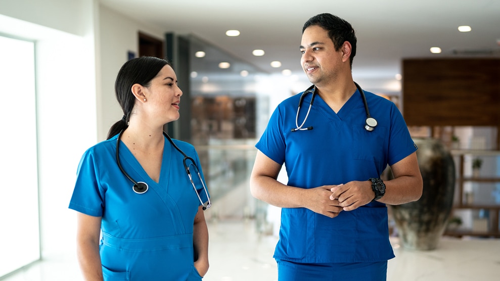 2 hospital workers conversing in hallway