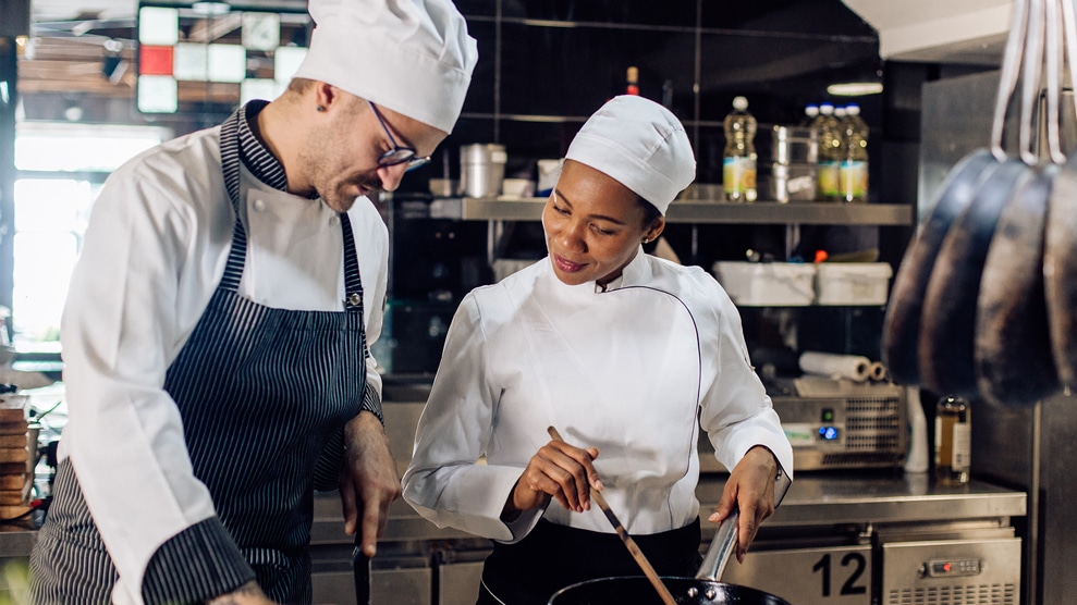 2 restaurant workers conversing in the kitchen