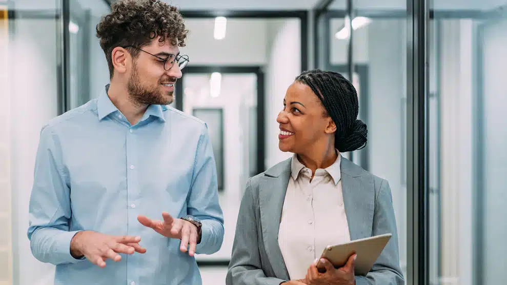 man and woman conversing in office hallway