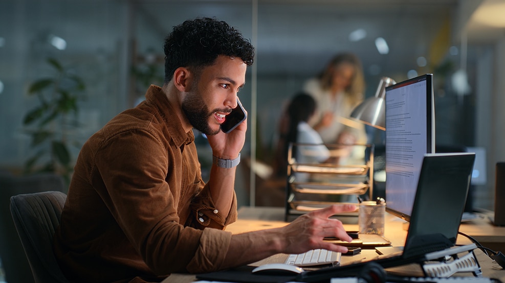 man at desk on the phone and computer